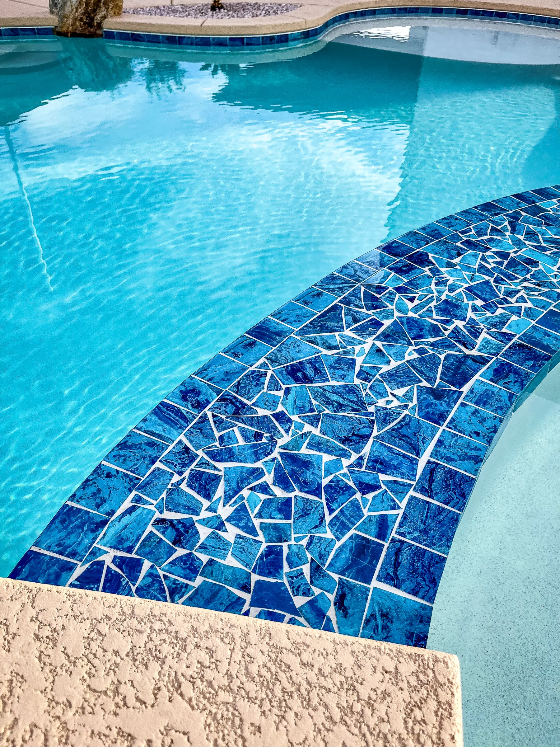 Blue mosaic tile and curved in-pool bench detail
