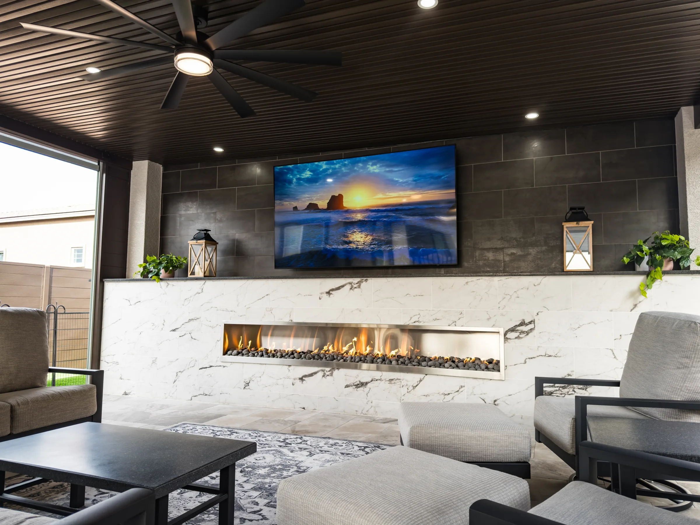 Covered patio with fireplace, television, and ceiling fan