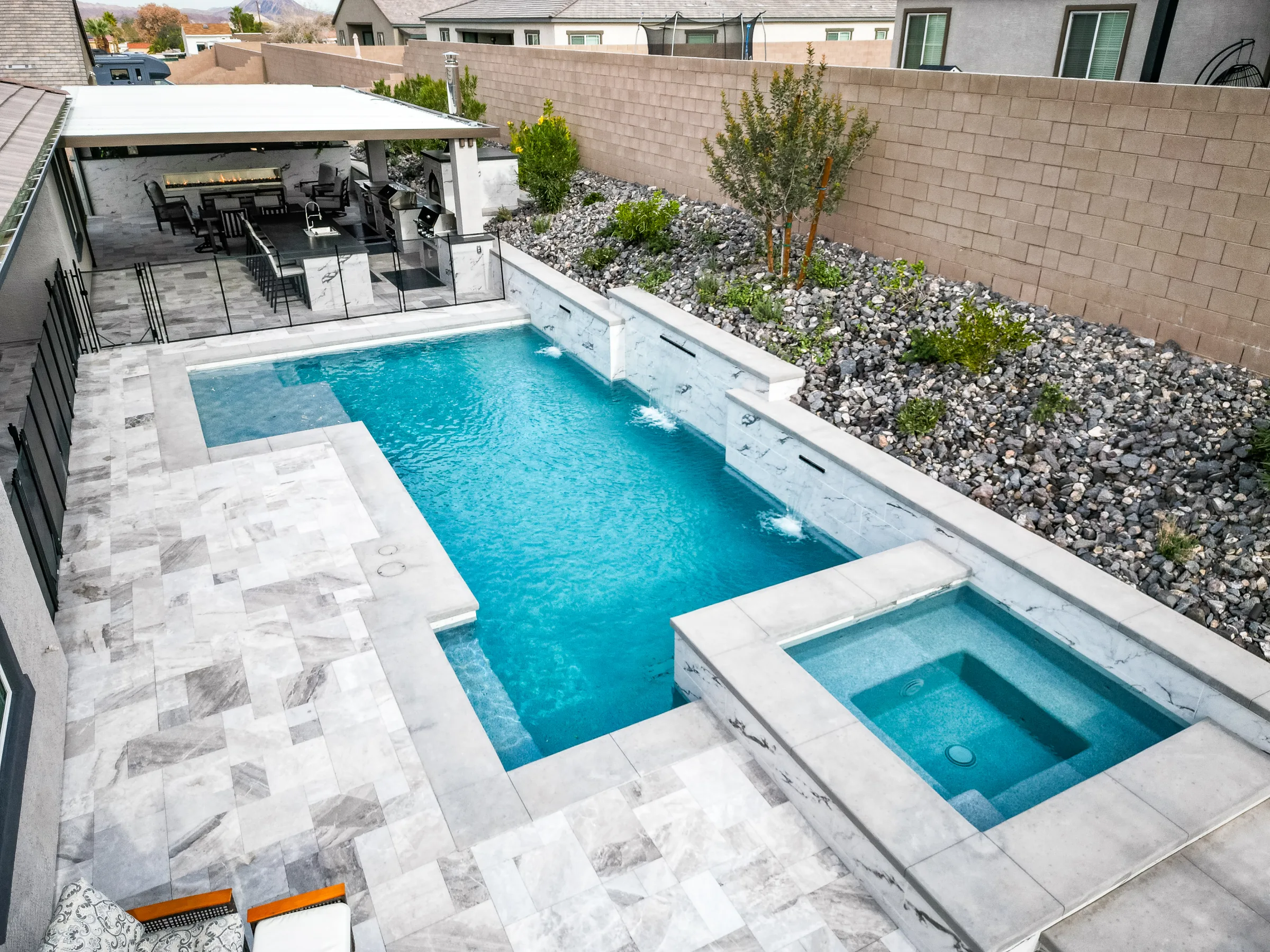 Aerial view of a pool, spa, covered patio, and landscaped backyard