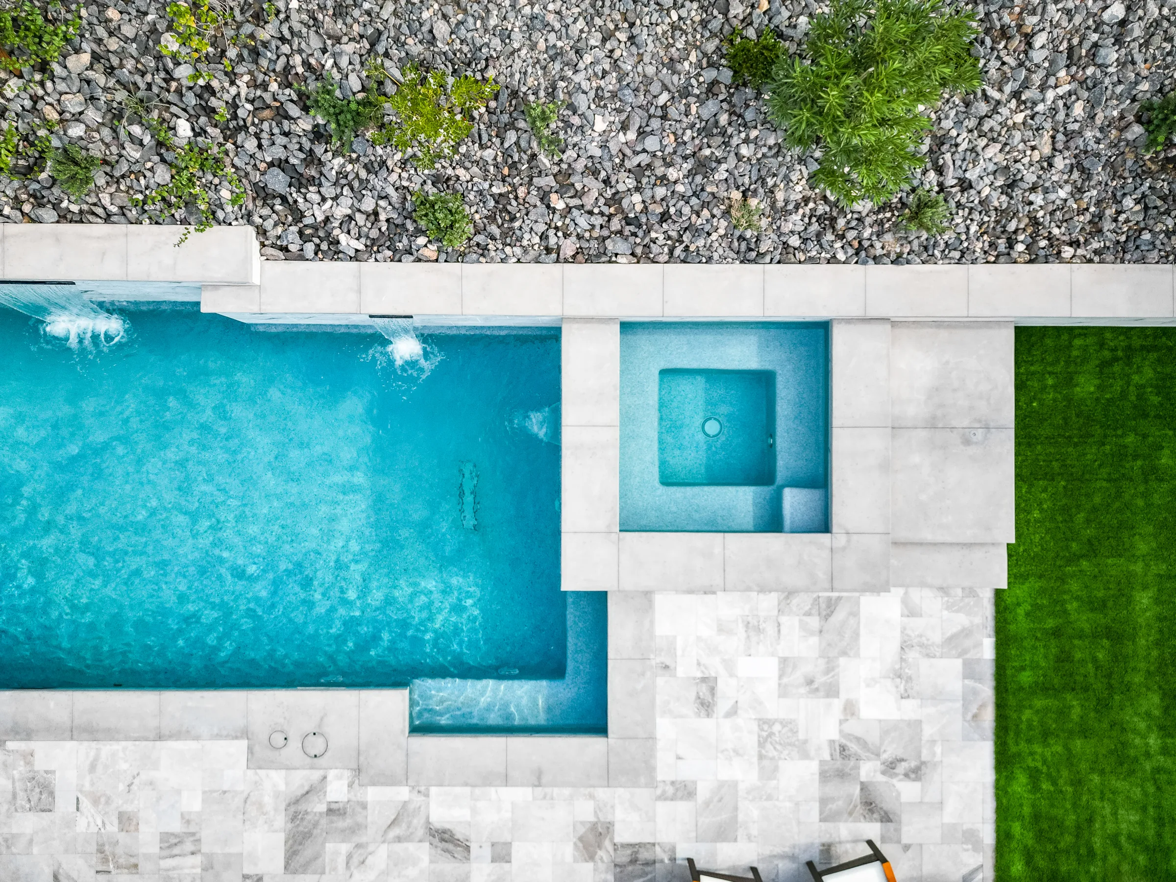 Top-down view of a pool, spa, geometric turf, and desert landscaping