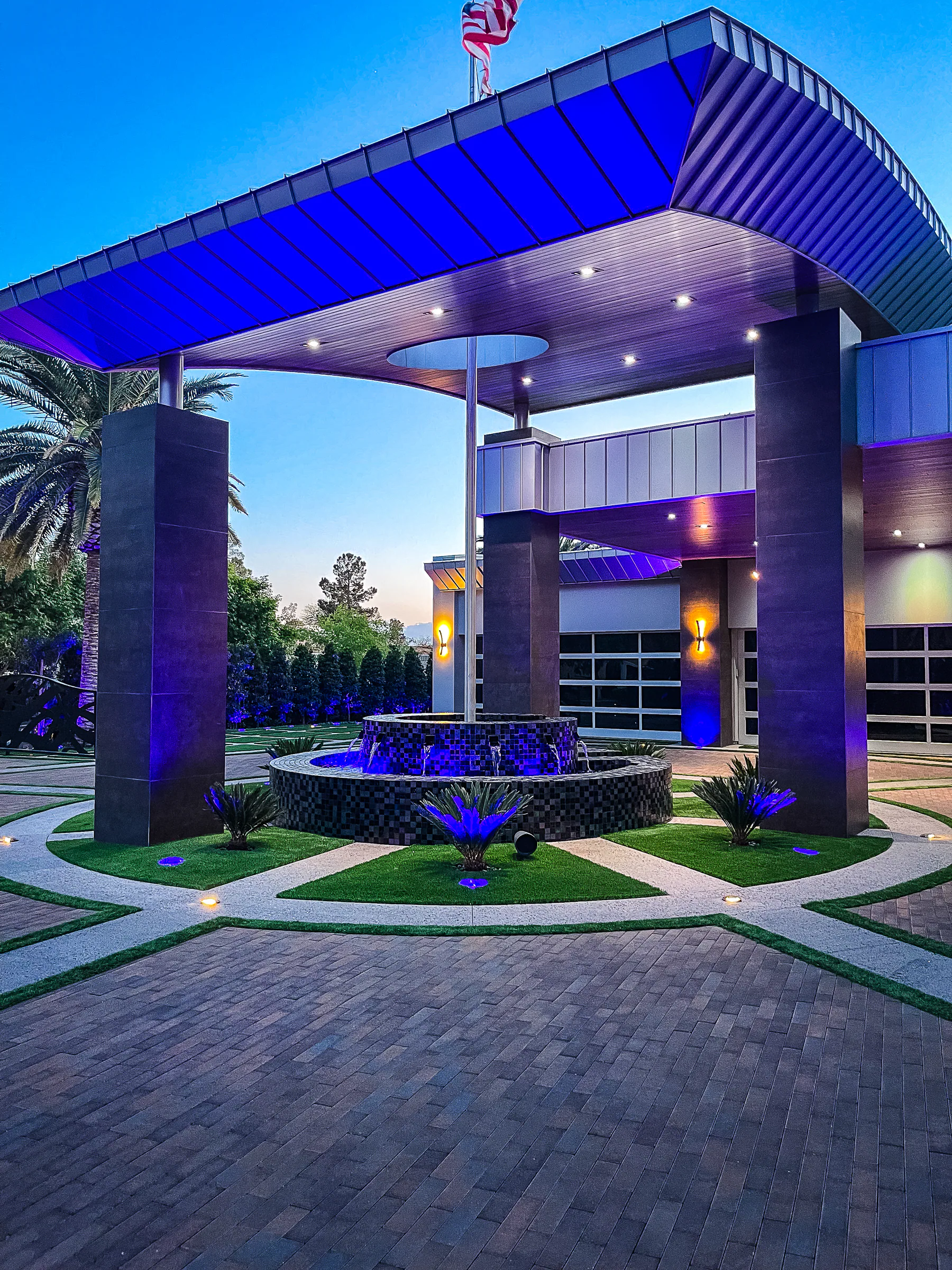 Custom black-tiled fountain beneath the curved porte cochere with palms and turf inlays
