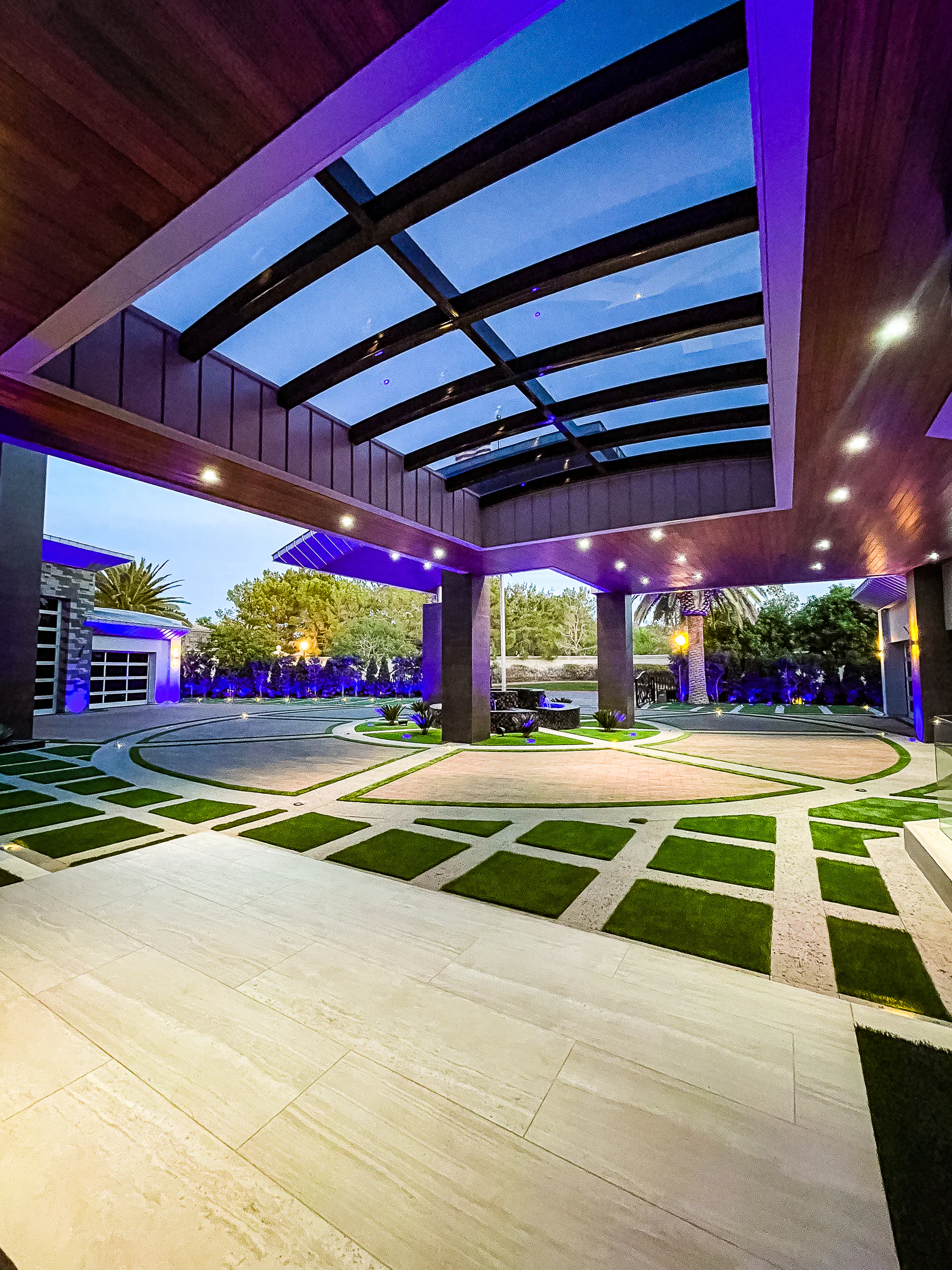Circular motor court beneath the wood-lined porte cochere with geometric turf bands