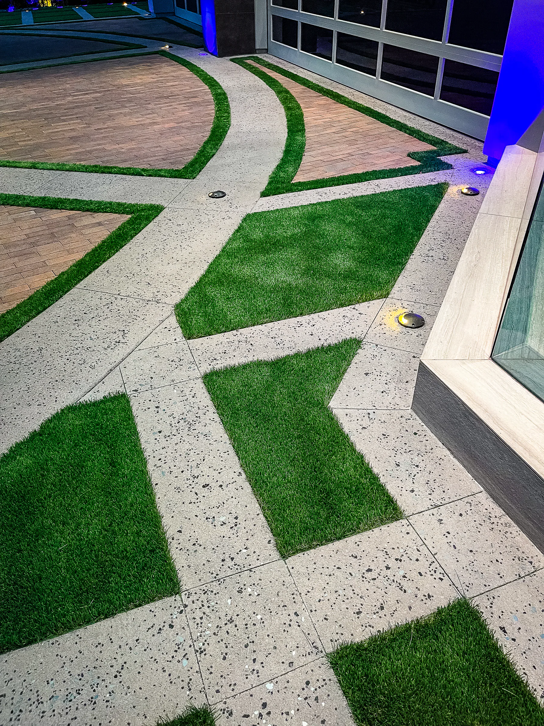Close view of exposed-aggregate paving and angular synthetic-turf inlays