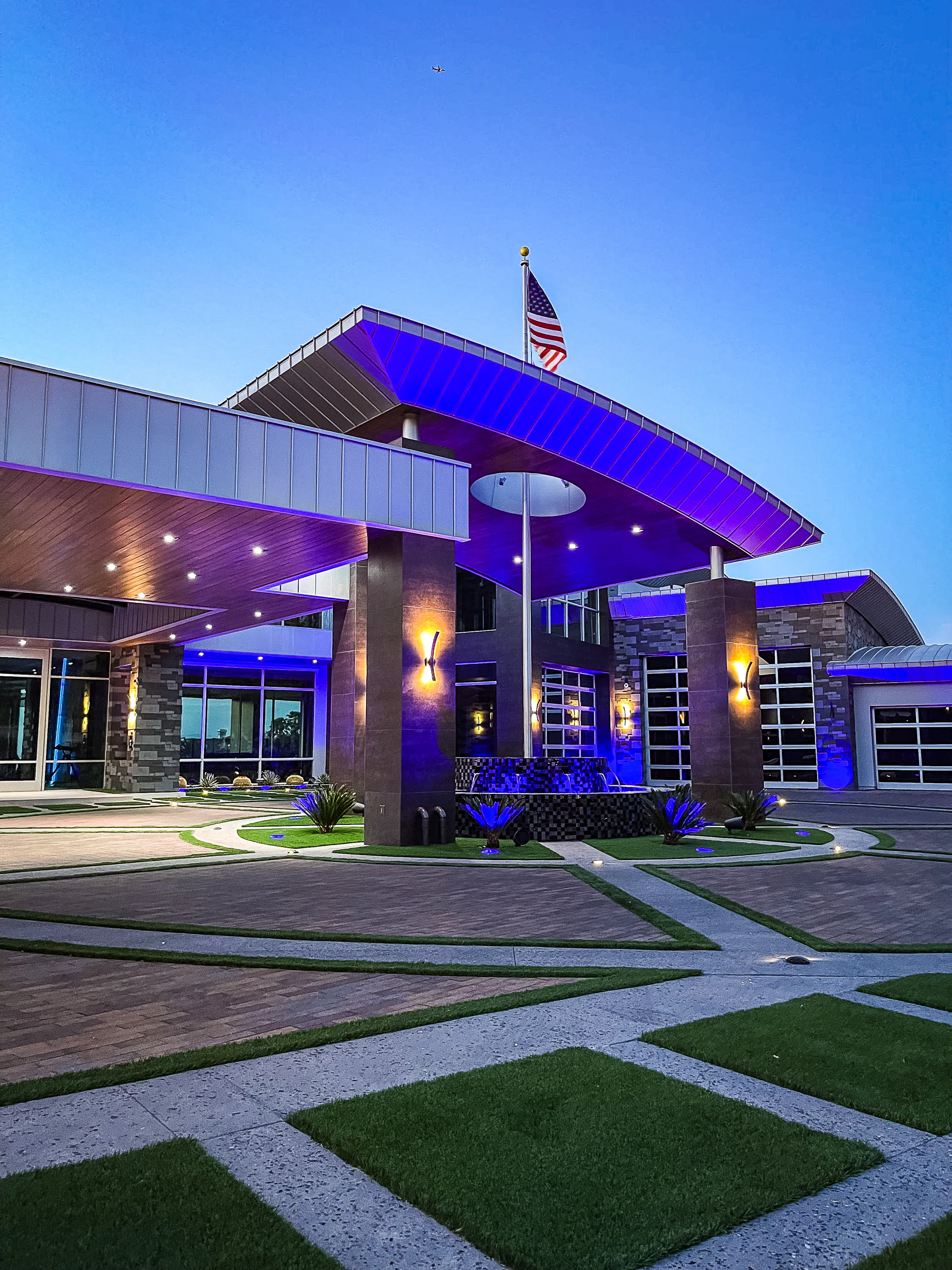Illuminated porte cochere and tiled fountain at the modern estate entrance