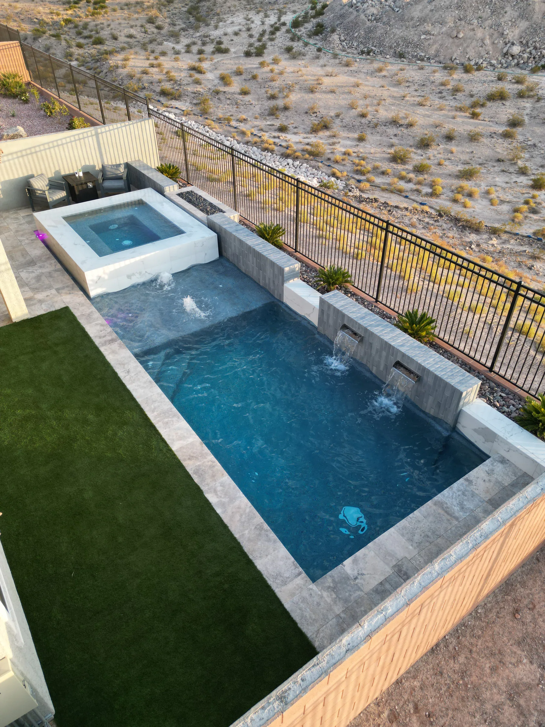Completed pool and raised spa filled with water in the finished backyard