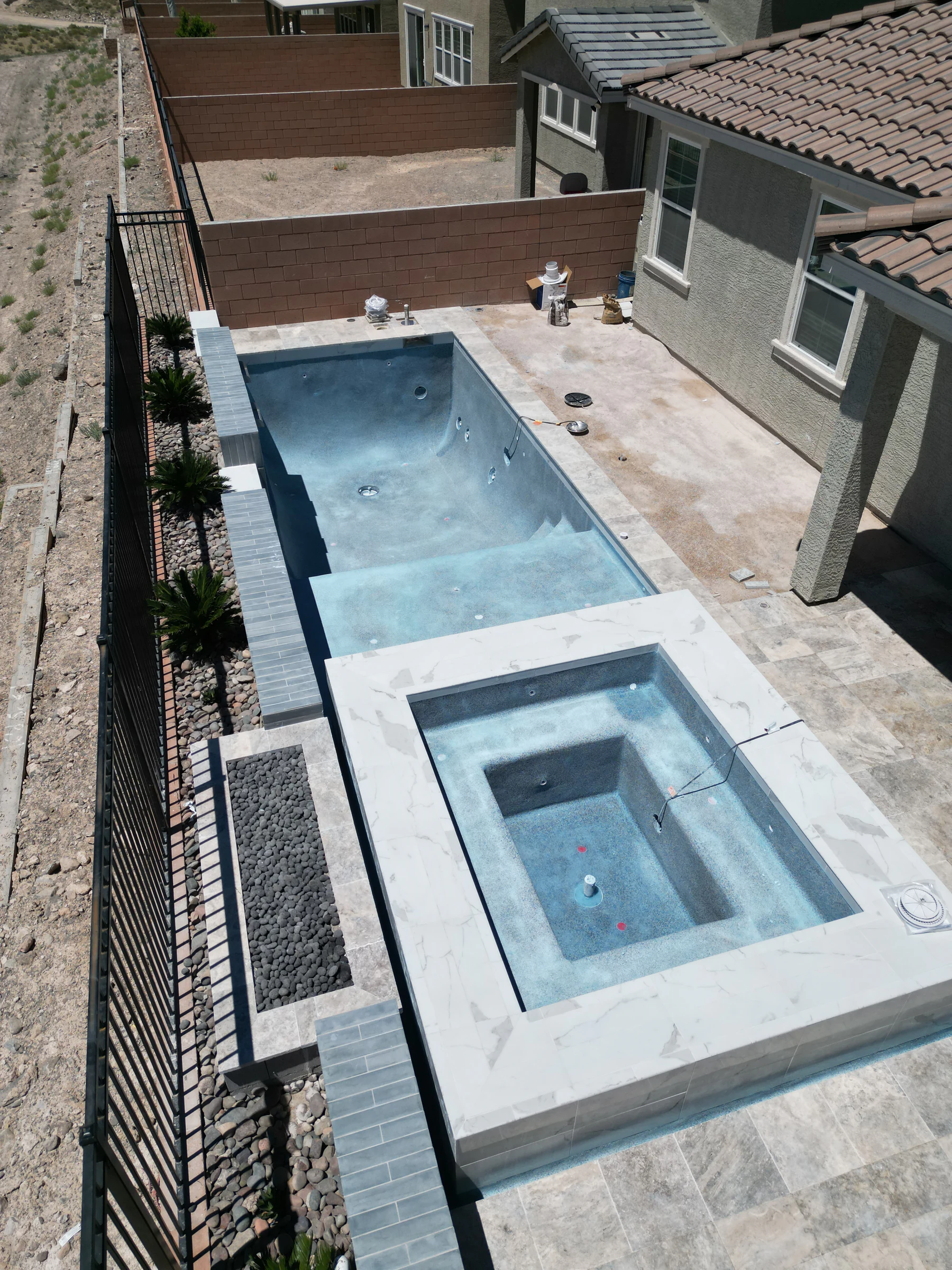 Fresh plaster, marble coping, raised spa, and pool before filling