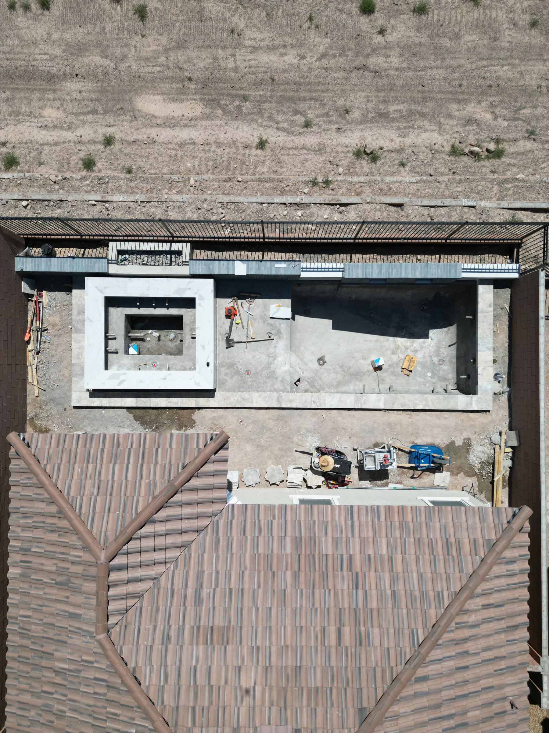 Pool and raised spa with waterline tile and coping installation underway