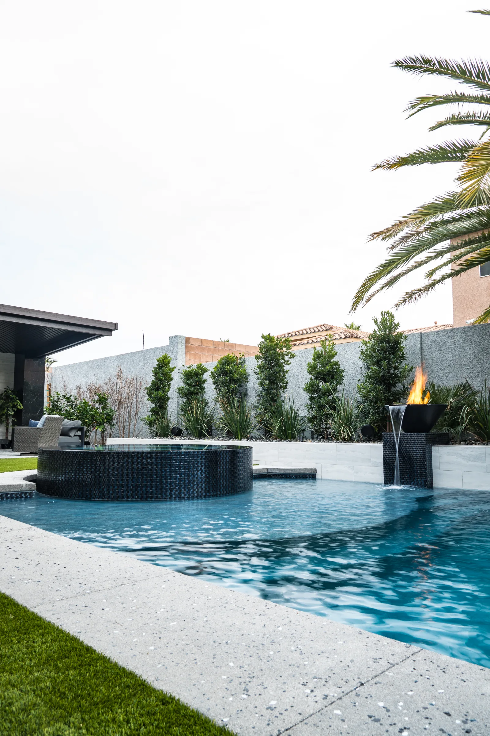 Outdoor BBQ island with grill, hedge, and white pavers