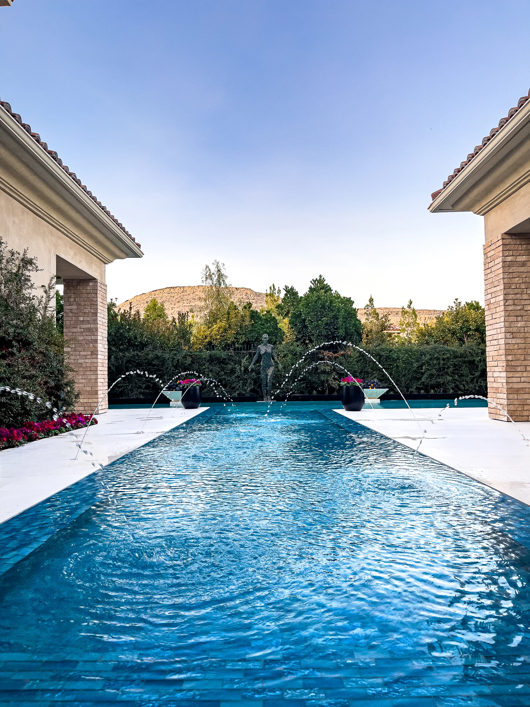Courtyard pool with deck jets, statue, and mountain backdrop