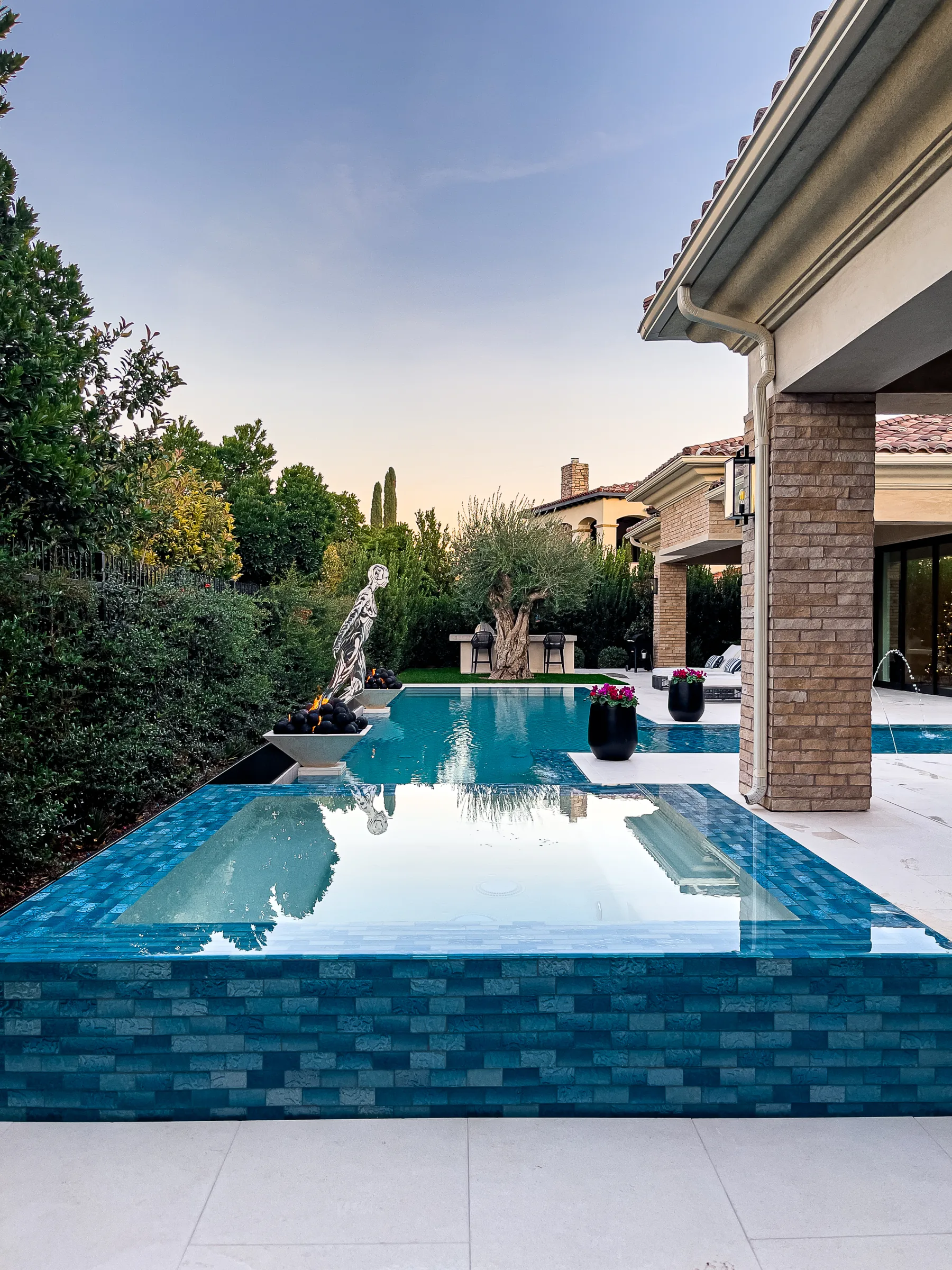 Overflow spa with statue, brick columns, and olive tree