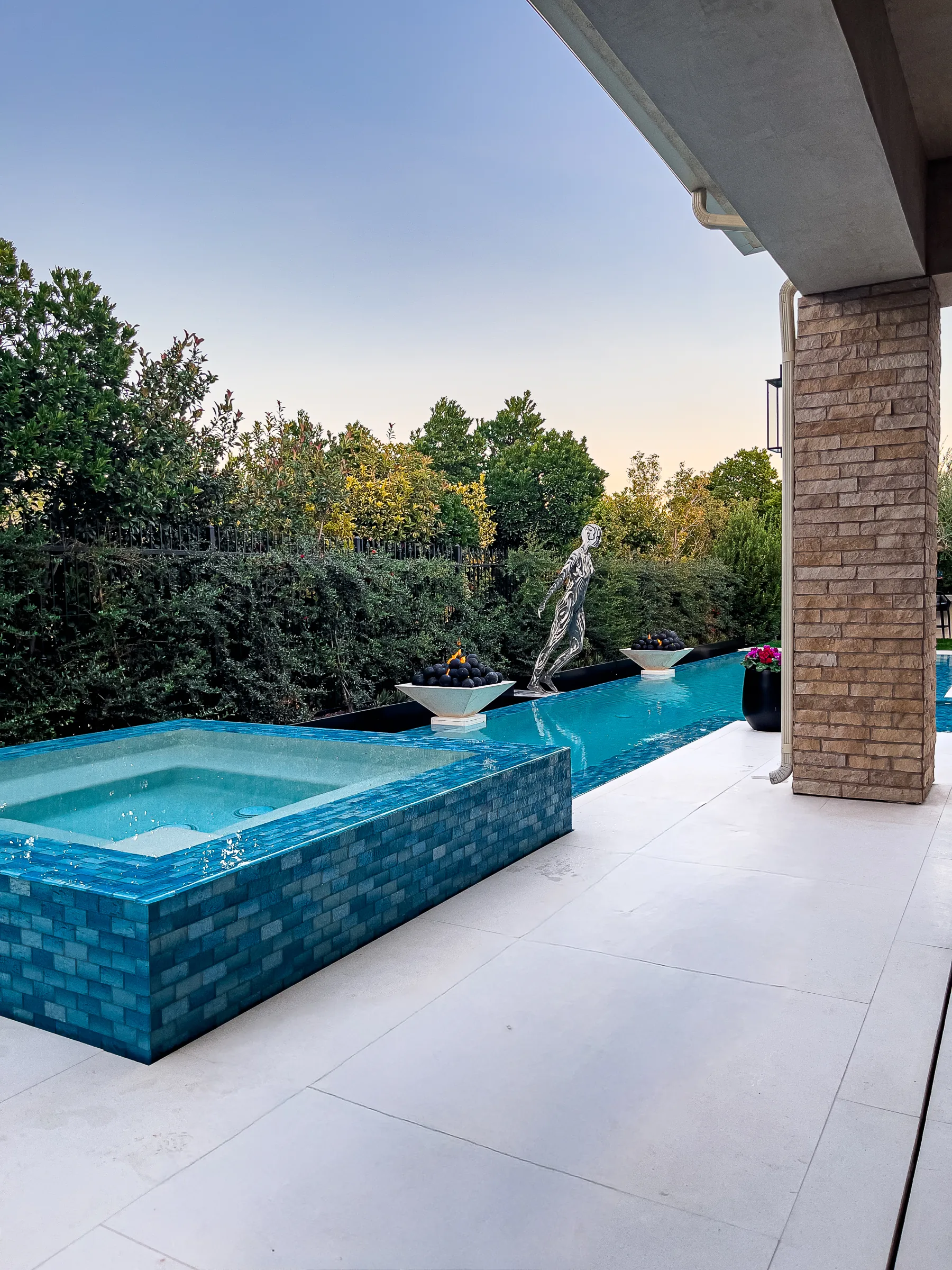 Blue-tile spa beside a patio, statue, and desert planting