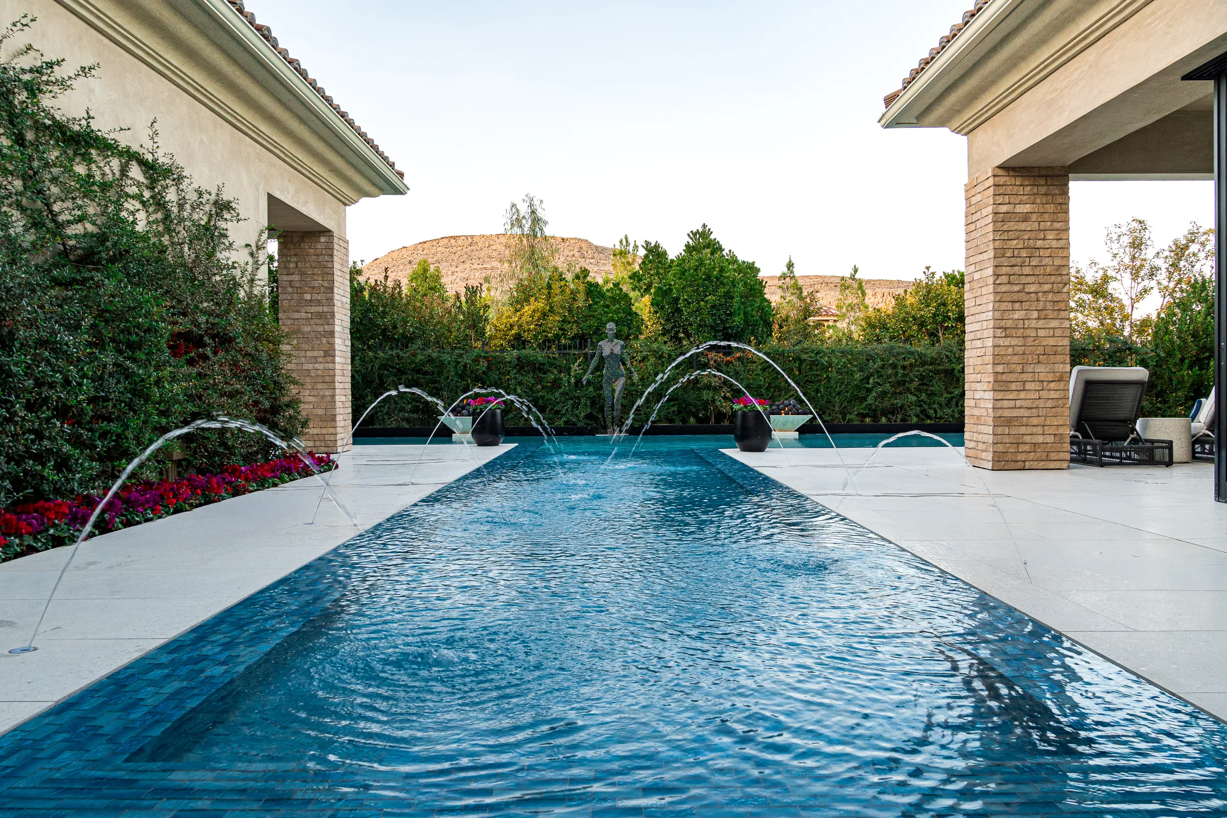 Finished courtyard pool with water jets, loungers, and a mountain backdrop
