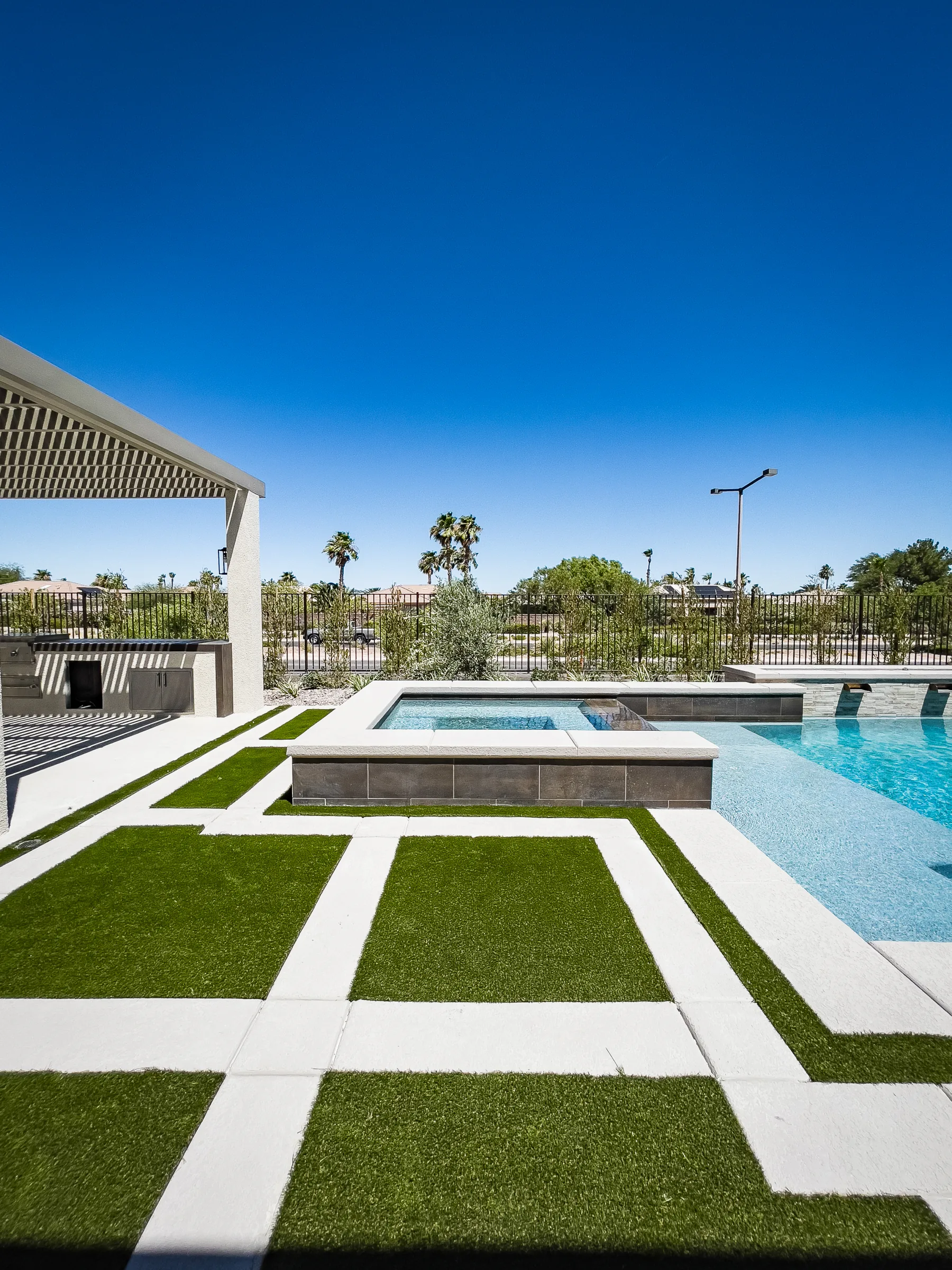 Completed pool, spa, pergola, and outdoor kitchen at dusk