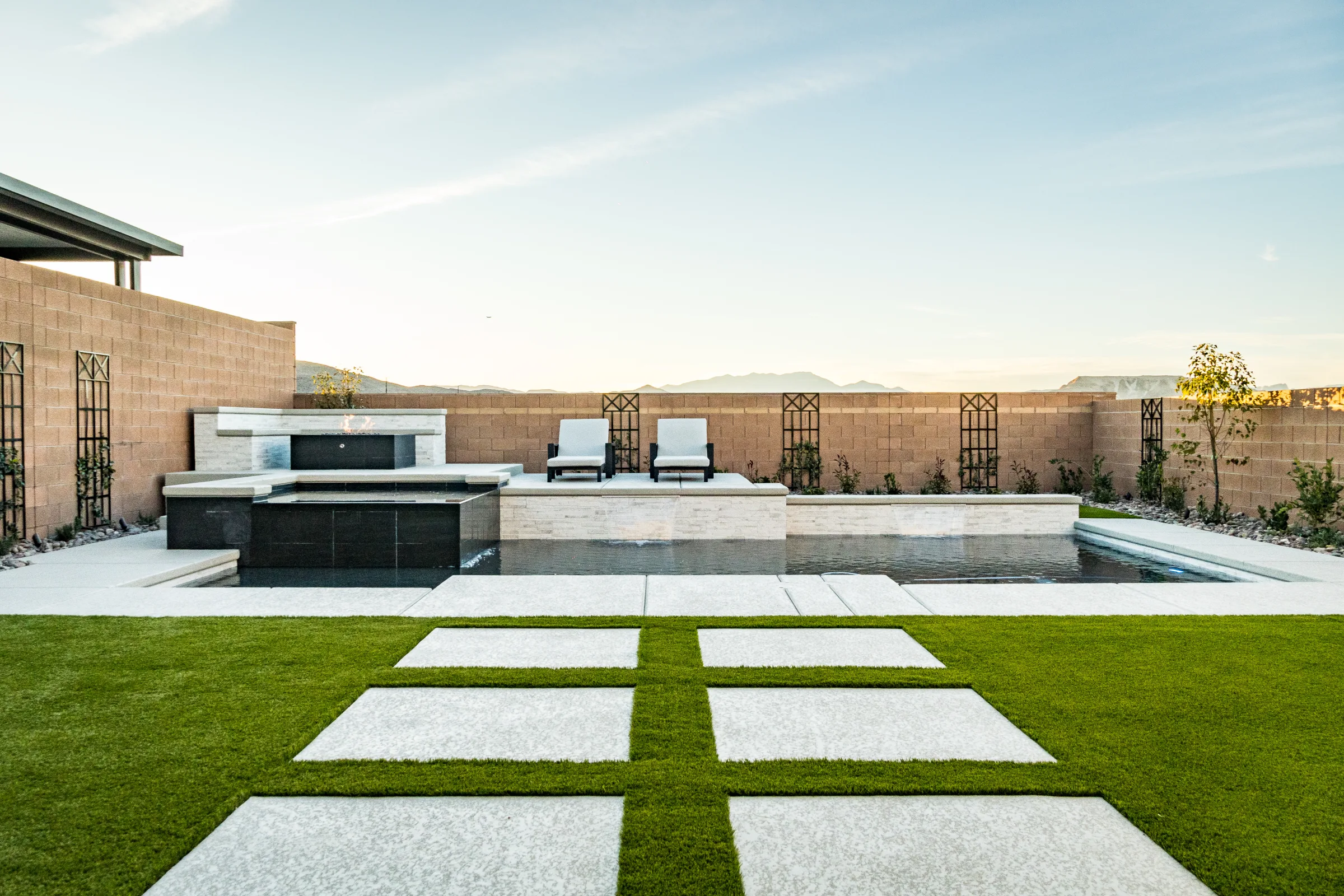 Symmetrical backyard pool with pavers, turf, and mountain backdrop