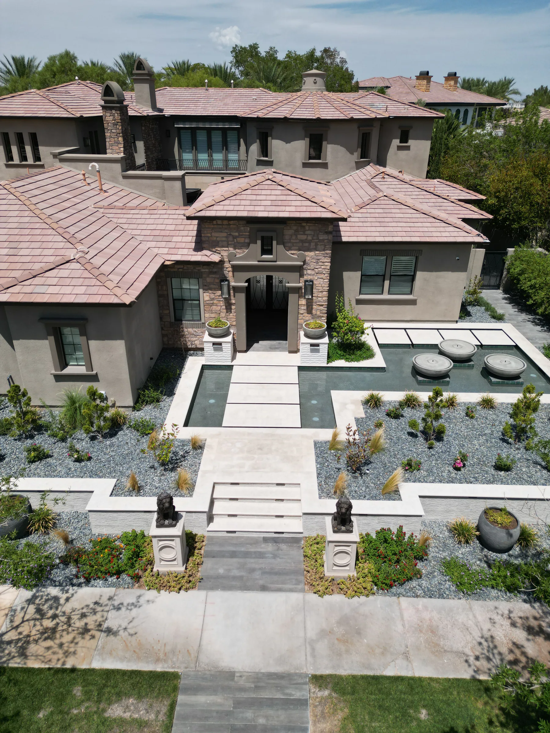 Straight-on drone view of the entry walkway between reflecting pools and desert planting beds
