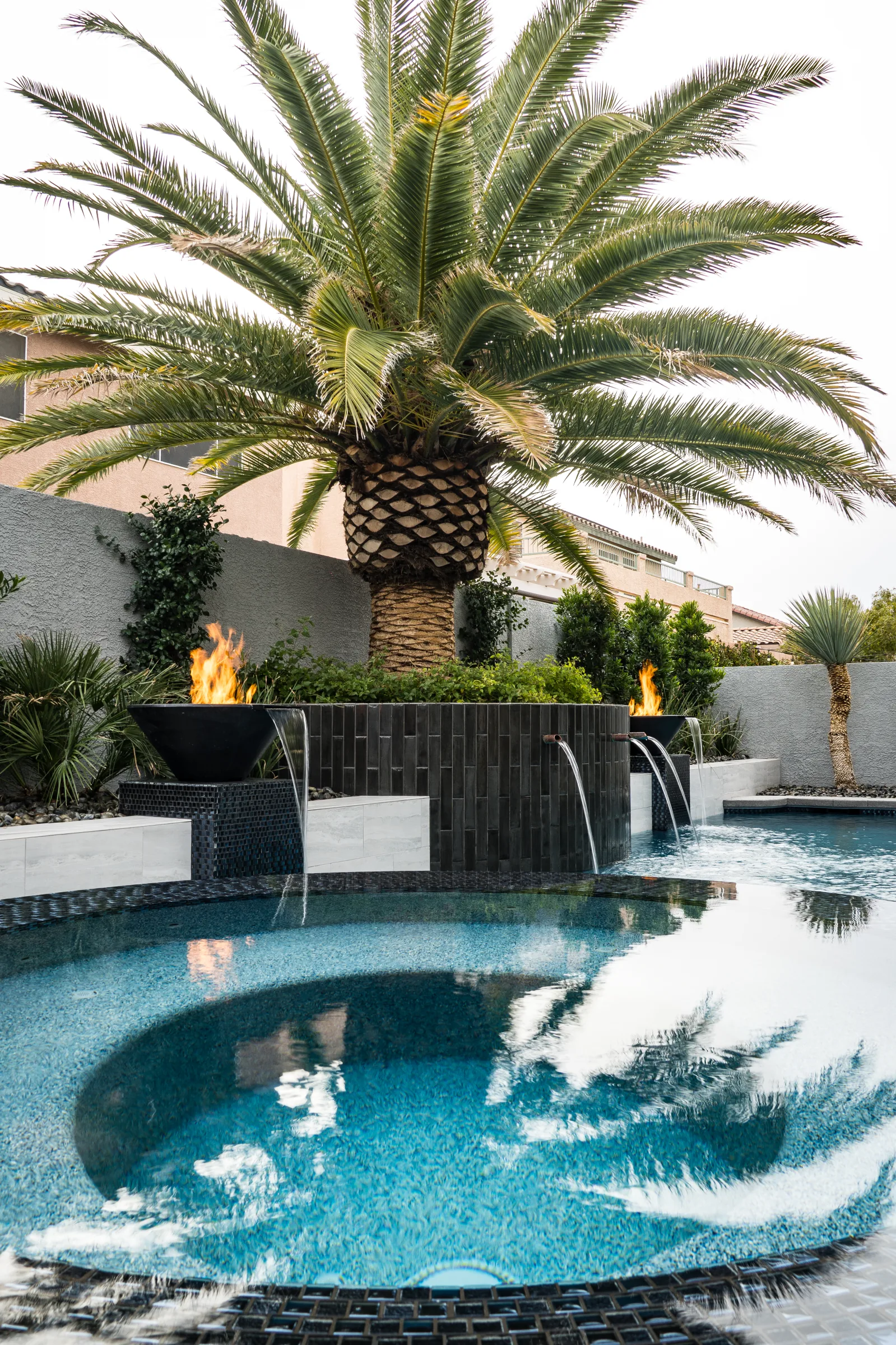 Spa with lit fire bowls and palm reflections in the water