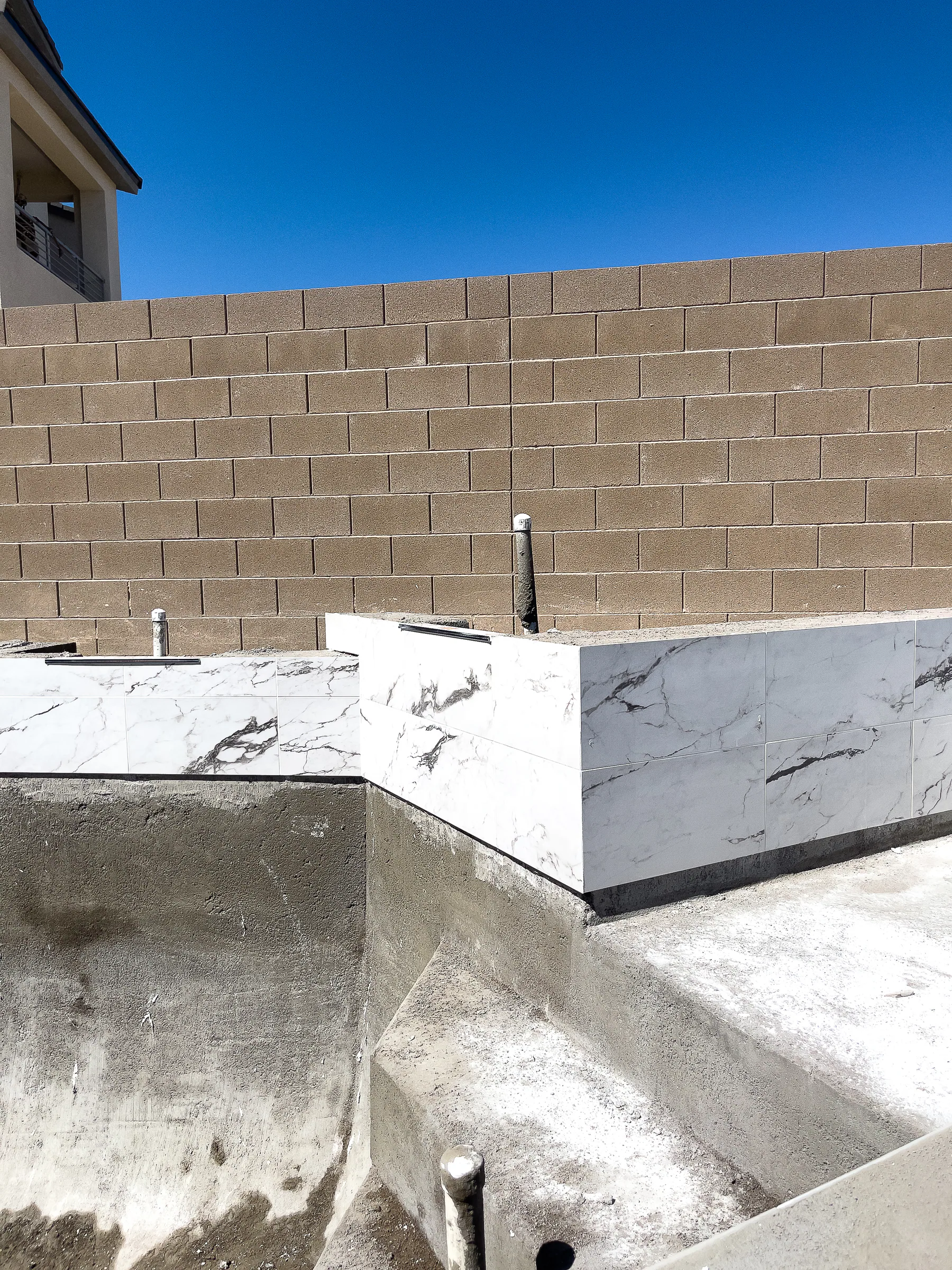 Marble-look tile going onto the raised spa wall during construction