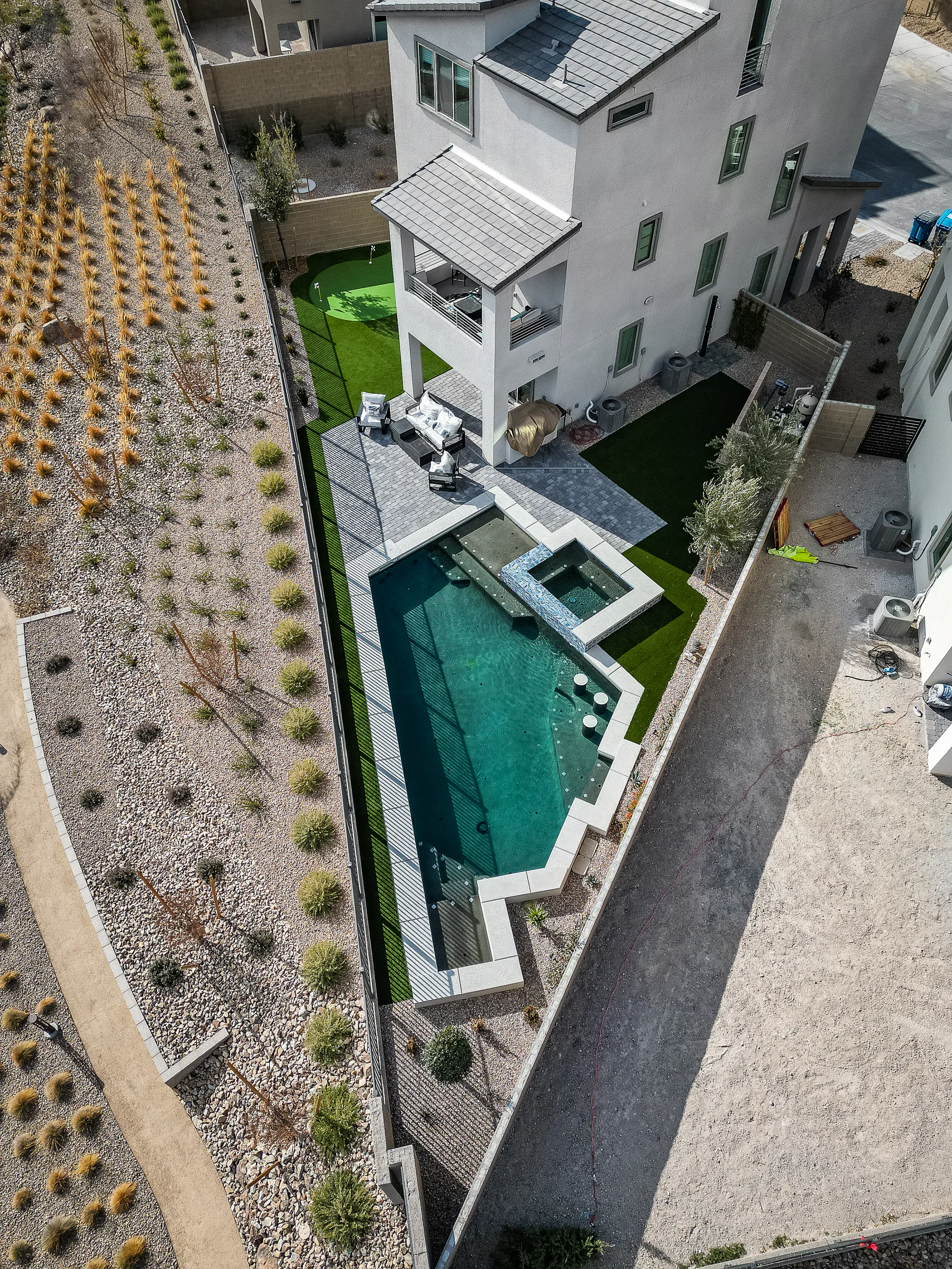 Aerial view of the completed geometric pool, raised spa, paver deck, and turf