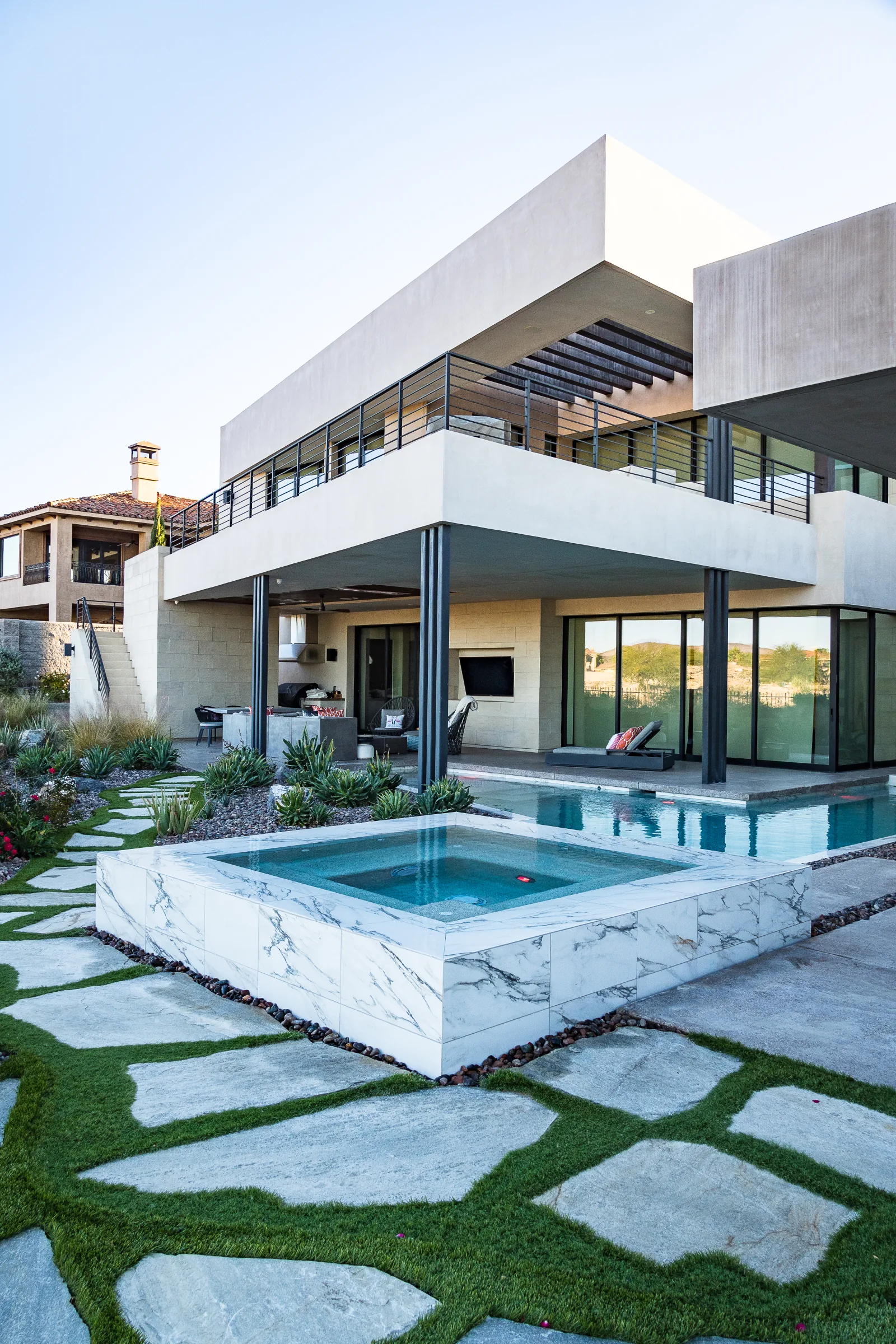Marble-clad spa and pool beside a flagstone path and modern home