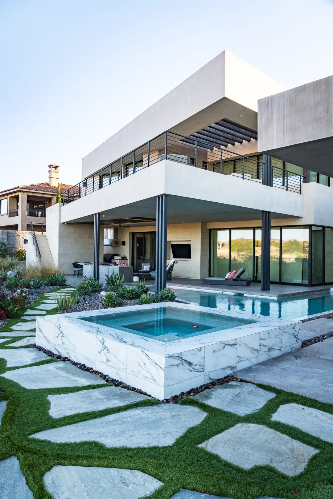 Marble-clad spa and pool beside a flagstone path and modern home