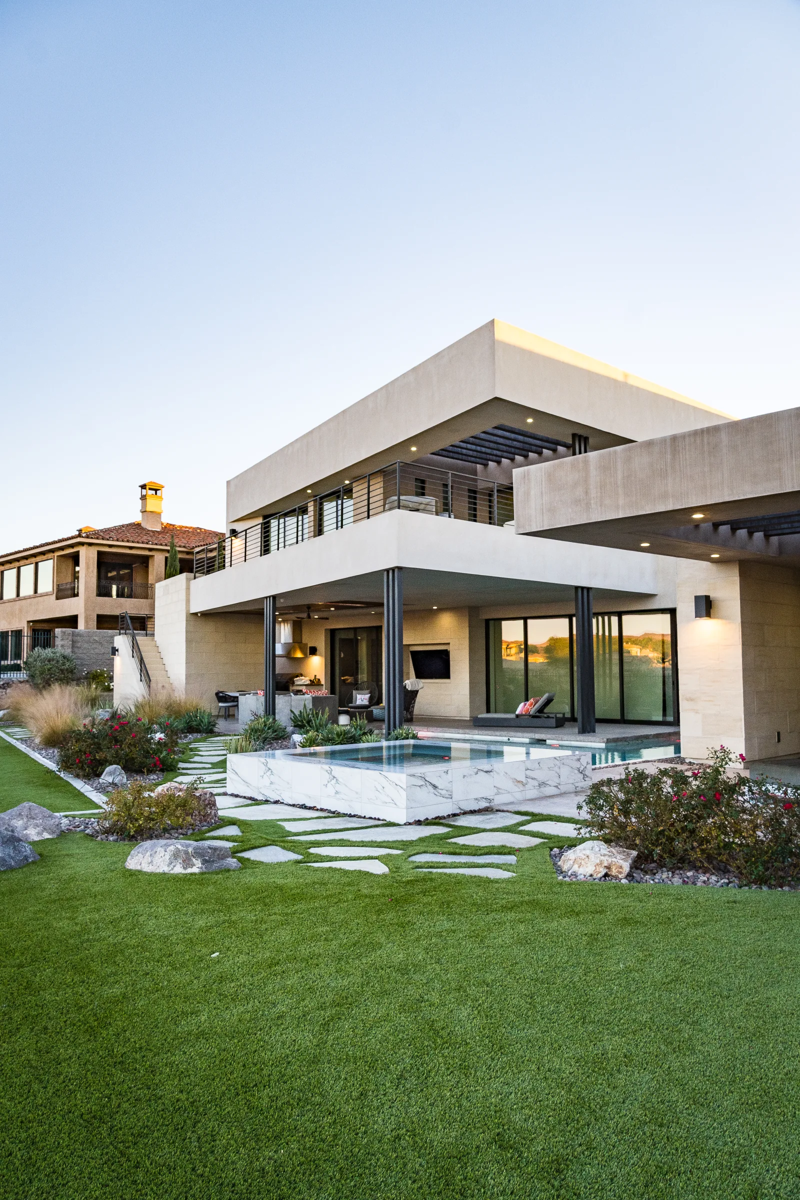 Wide lawn view of a marble spa beside a modern home
