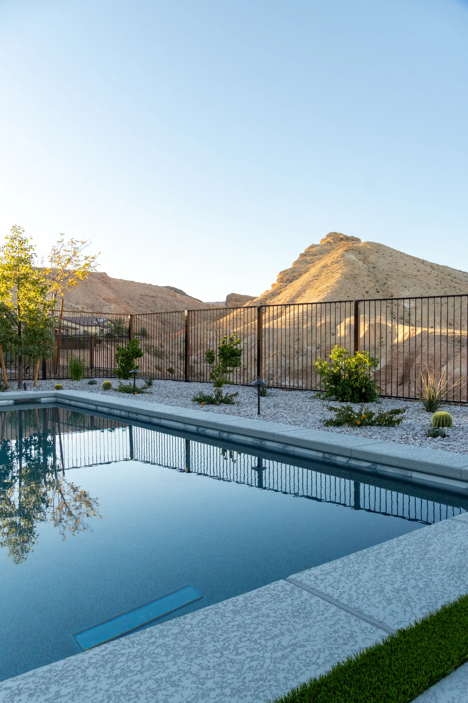 Reflective pool looking toward an iron view fence and desert hills