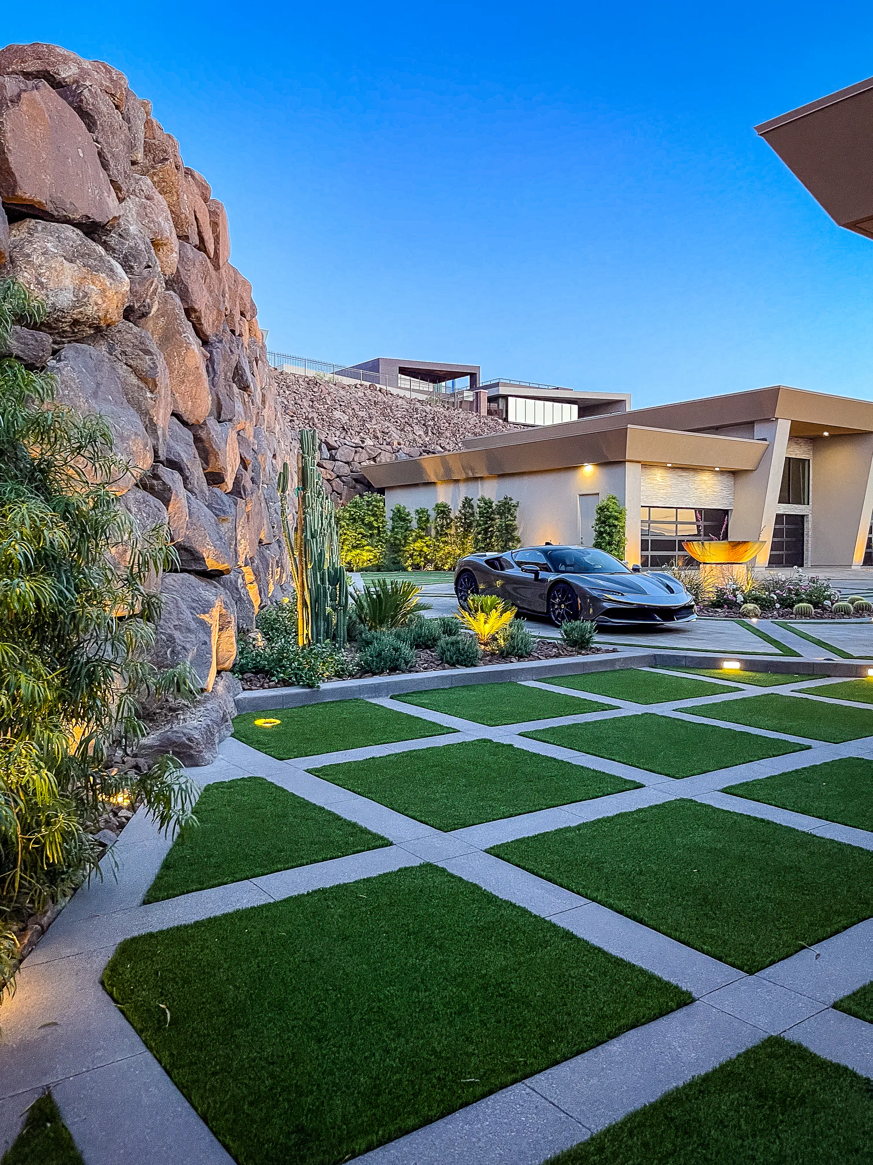 Sports car parked beside the turf-grid motor court and desert rock retaining wall