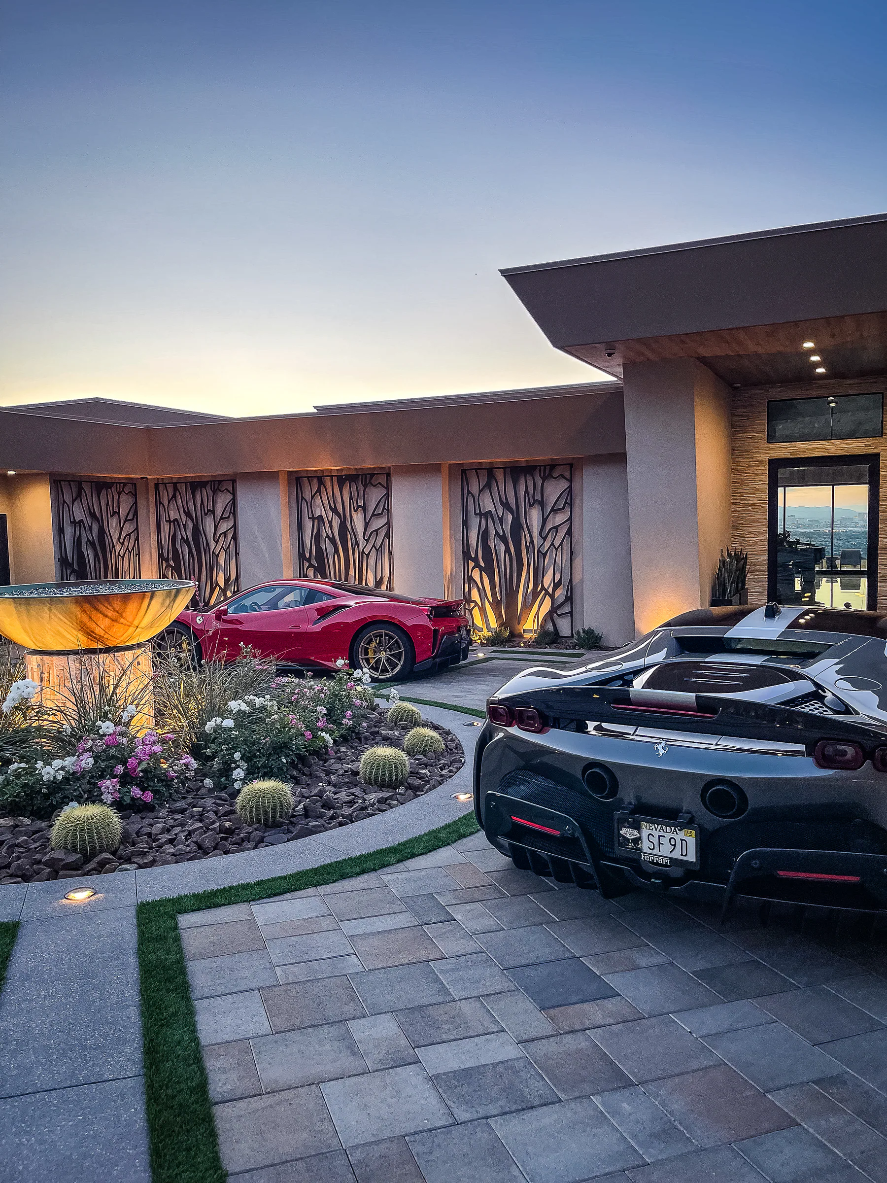 Circular fountain court with flowering desert plants and sports cars at the front entry