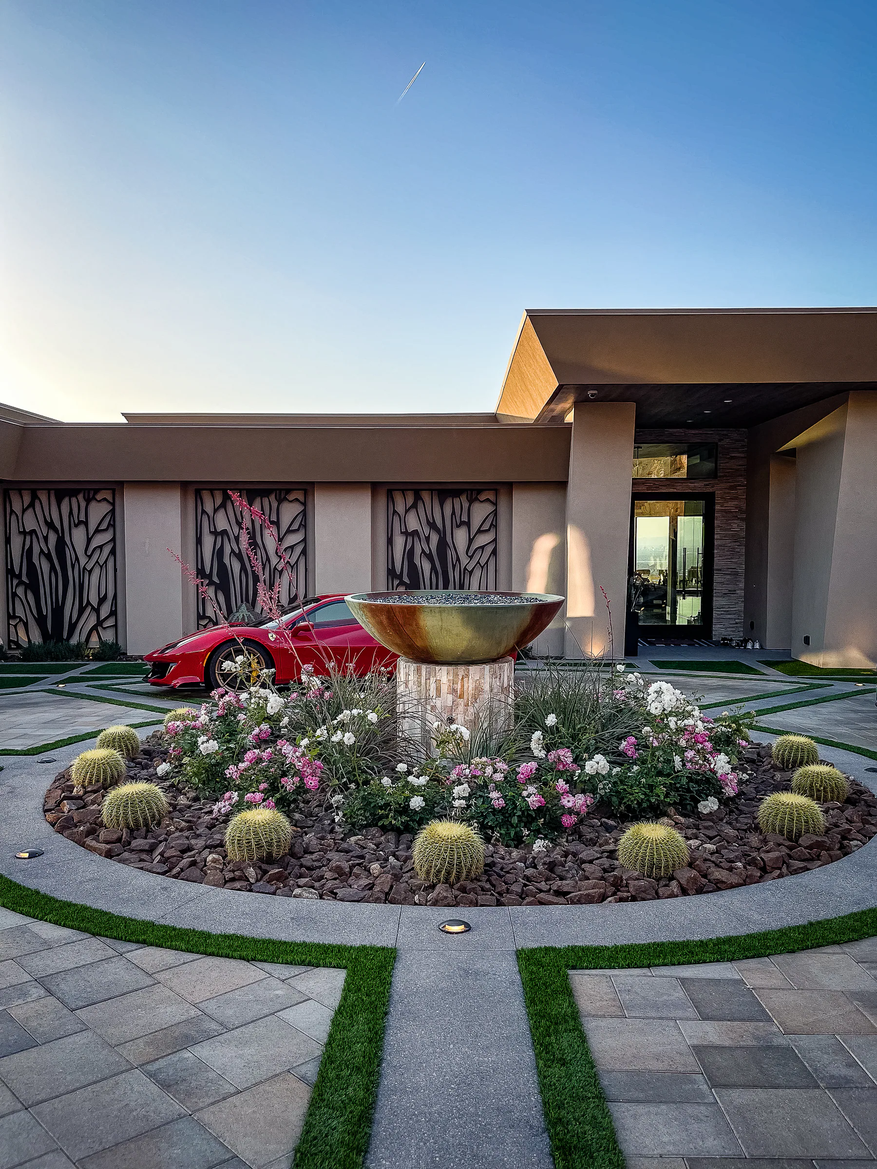 Red sports car behind the custom fountain and cactus garden at the estate entrance